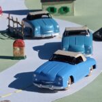 vue de 3 Panhard Dyna Junior CIJ de 3 nuances de bleu négociant un virage dans un cartificiel