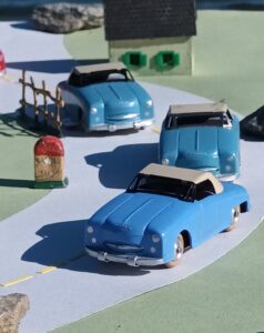 vue de 3 Panhard Dyna Junior CIJ de 3 nuances de bleu négociant un virage dans un cartificiel