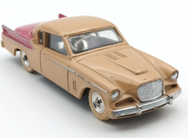 Vue de 3/4 avant de la Studebaker Golden Hawk Dinky Toys GB biclore café au lait et rouge framboise avec roues en aluminium