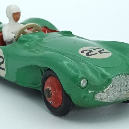 Vue de 3/4 avant d'une Aston Martin DB3S/4 de 1953reproduite par Dinky Toys GB verte avec numéros de course, son châssis est oxydé, des traces d'humidité sur la peinture rouge des roues, les numéros ont des petits manques