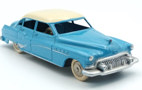 Vue de 3/4 avant d'une Buick Roadmaster 1952 berline Dinky Toys France 24V bleue à toit crème avec intérieur du toit quadrillé, roues chromées avec boite en état moyen sans ombre conforme au modèle