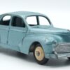 Vue de 3/4 avant d'une Peugeot 203 Dinky Toys France bleu vert métallisée avec petite lunette et bouchon d'essence sur l'aile arrière droite