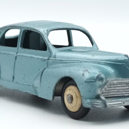 Vue de 3/4 avant d'une Peugeot 203 Dinky Toys France bleu vert métallisée avec petite lunette et bouchon d'essence sur l'aile arrière droite