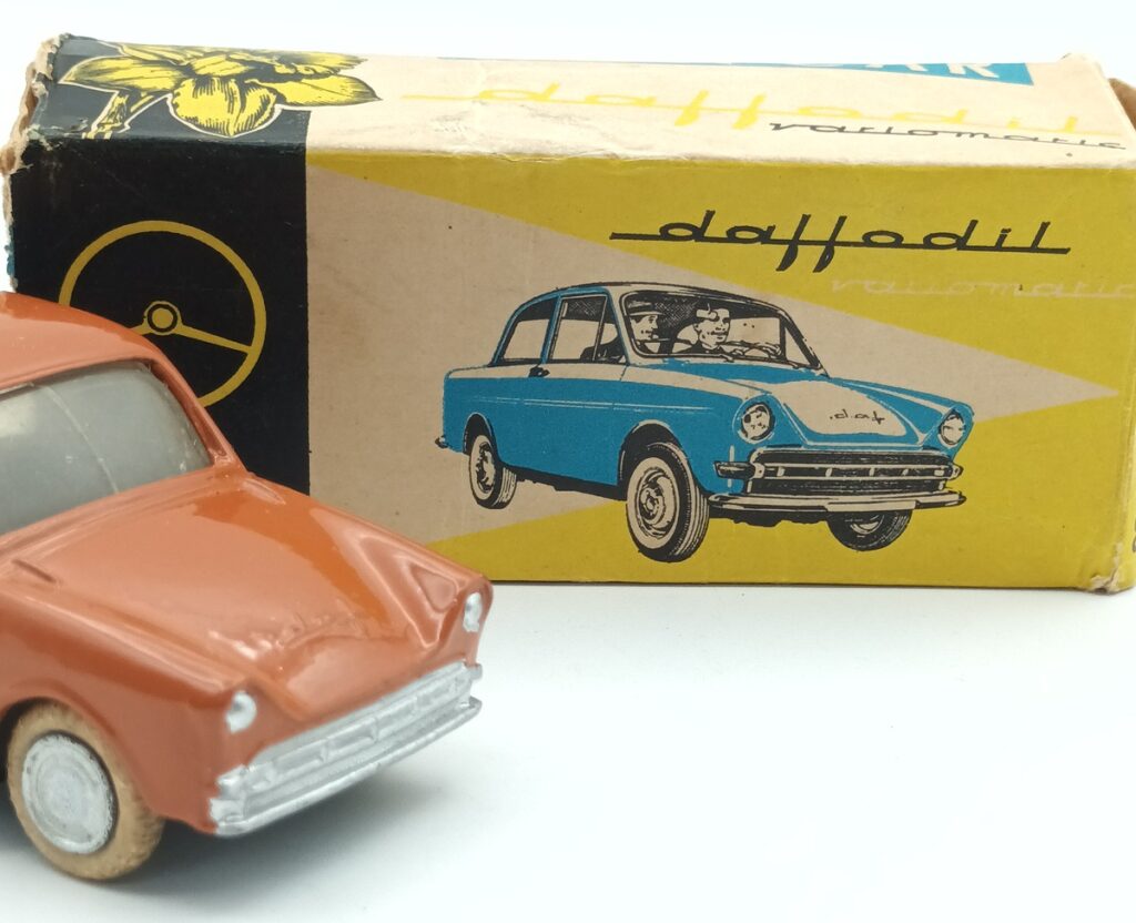 3/4 avant d'une Daffodil 30 LION CAR repeinte en orange brique devant sa boite