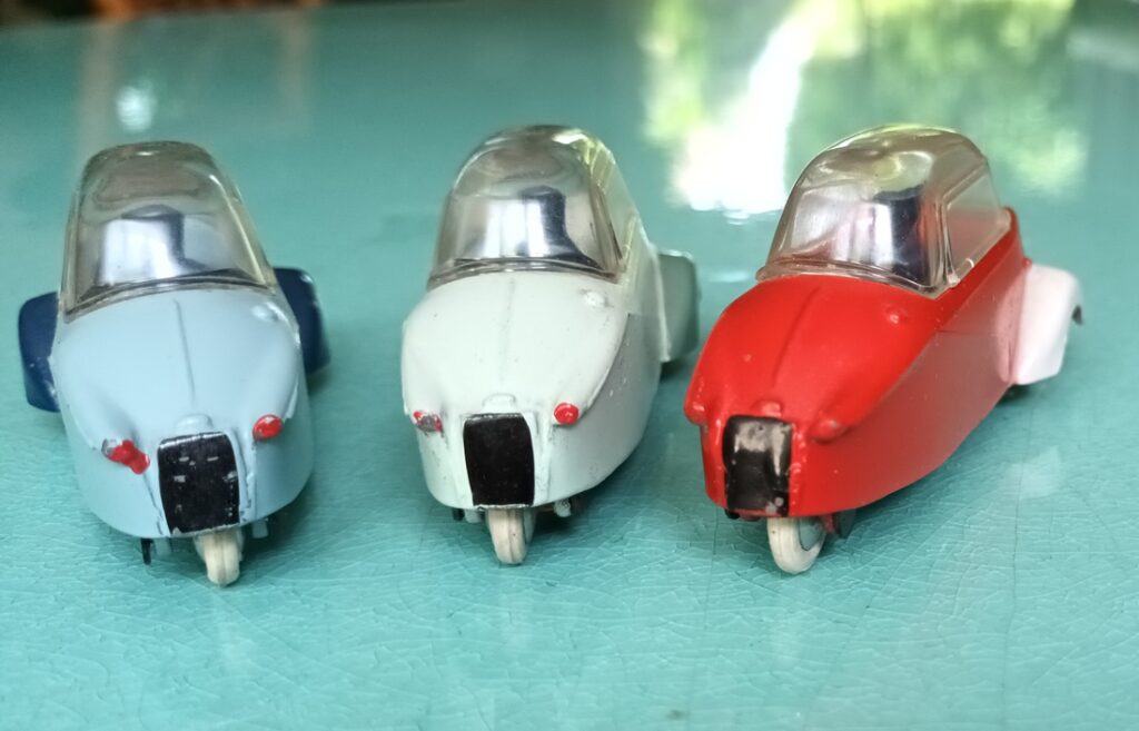 Trois Messerschmitt KR 200 Quiralu bicolores de profil négociant un virage relevé : de couleurs rouge/blanc, bleu Vue arrière en éventail de trois Messerschmitt KR 200 Quiralu bicolore : de couleurs rouge/blanc, bleu clair/ bleu soutenu, vert d'eau/ vert gris