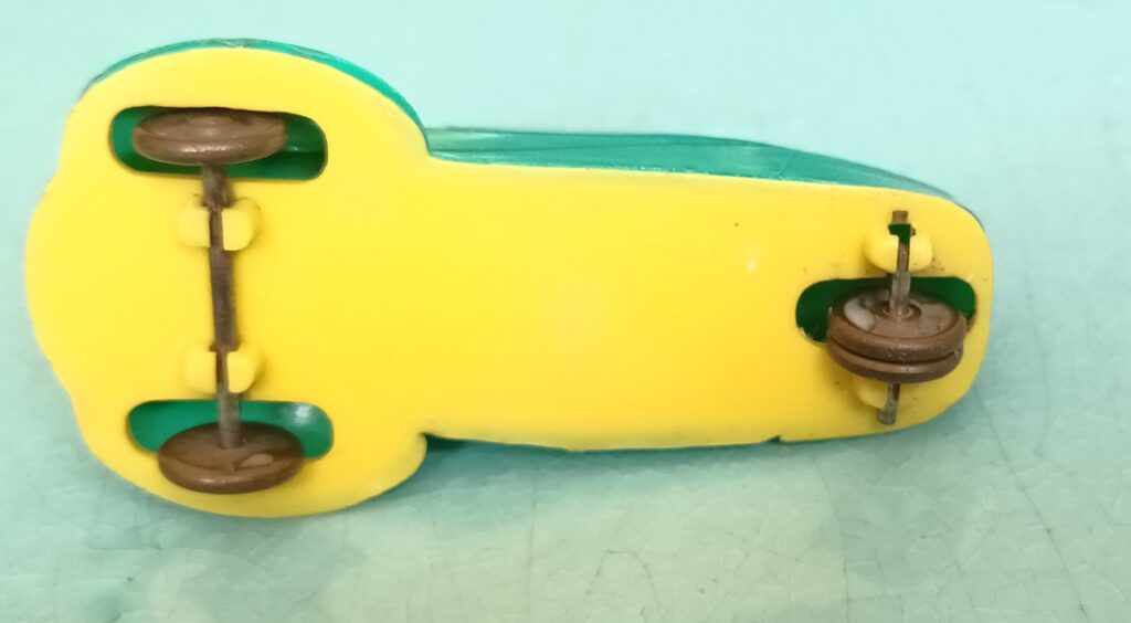 Vue de dessous de la Messerschmitt KR JUNO Plast verte avec un châssis jaune lisse et des roues en Laiton