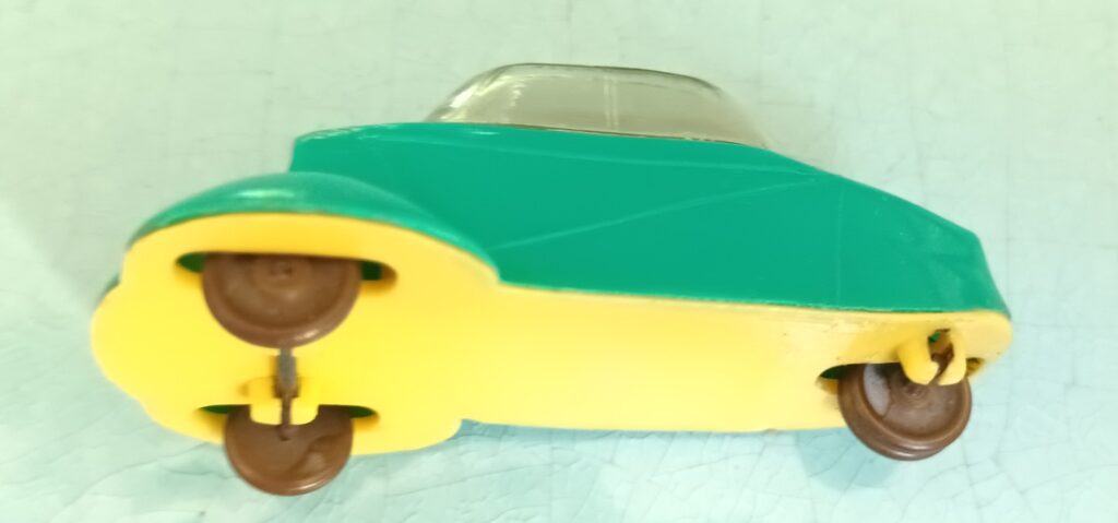 Vue du dessous et du côté gauche de la Messerschmitt KR JUNO Plast verte avec un châssis jaune lisse et des roues en laiton