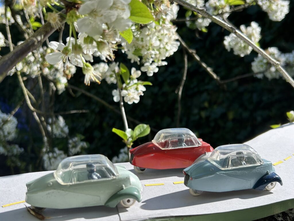 3 Messerschmitt KR 200 Quiralu se suivant sur une route sur fond de fleurs de cerisier